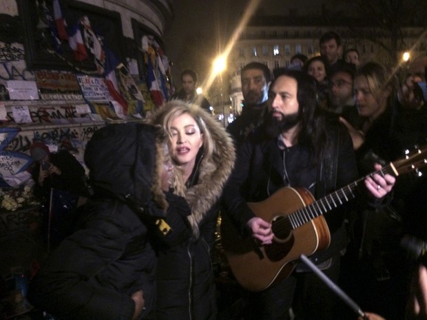 Madonna canta na Praça da República, em Paris, ao lado do guitarrista Monte Pittman e do filho dela David Panda (Foto: Jules Mahe/AFP)