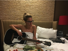 Lady Gaga posa nua na cama, enrolada em lençol, tocando violão