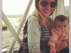 Debby Lagranha sorri para foto com filha no colo em aeroporto