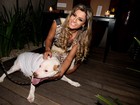 Com os cabelos longos e loiros, Babi Rossi posa com cachorro em evento