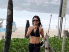 Ana Lima caminha na praia e exibe barriga sequinha