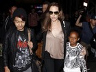 De blusa decotada, Angelina Jolie viaja com os filhos