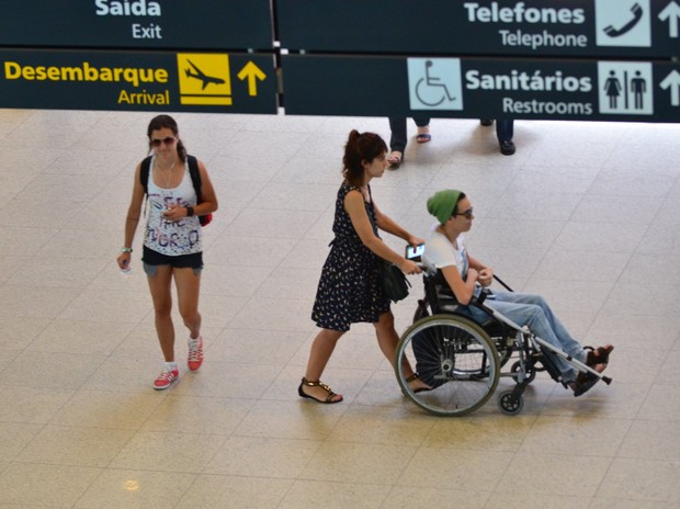 De cadeira de rodas, Maria Gadu embarca com namorada no aeroporto (Foto: FotoRioNews / William Oda)