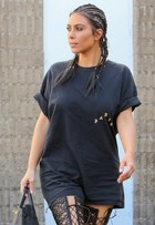 Kim Kardashian surge com penteado exótico e botas de cano altíssimo