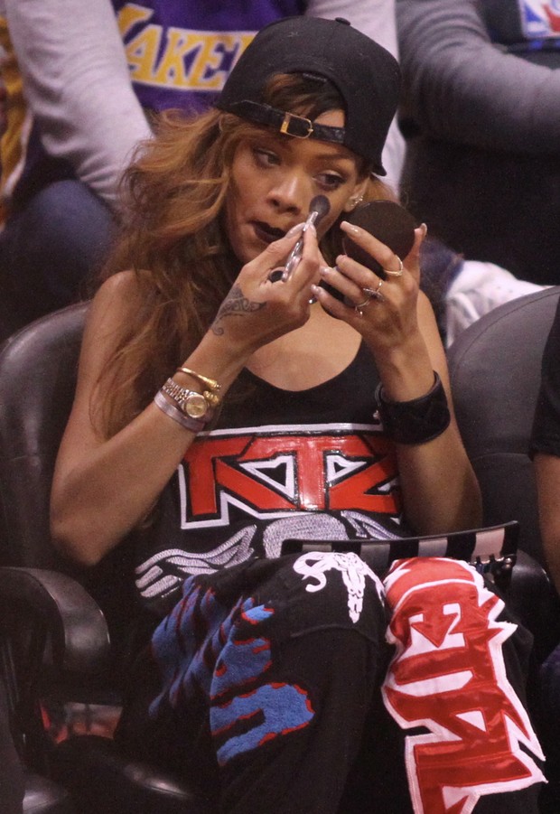 Rihanna retoca a maquiagem durante jogo de basquete em Los Angeles, nos Estados Unidos (Foto: Splash News/ Agência)