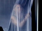 Acordada com fogos, Madonna espia atrás da cortina de janela do hotel