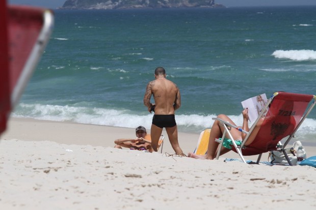 Felipe Tito e namorada na praia da Barra da Tijuca, RJ (Foto: Henrique Oliveira / FotoRioNews)