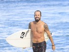 Paulinho Vilhena sai sorridente do mar após surfar