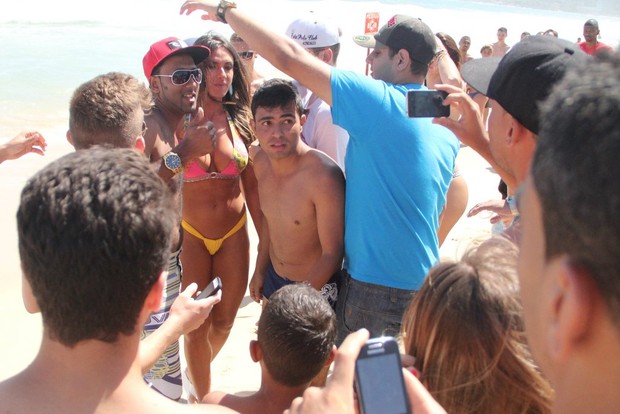 Nicole Bahls cercada por homens em praia (Foto: AgeNews/Rodrigo dos Anjos)