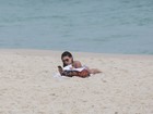 Isis Valverde vai sozinha a praia e coloca a leitura em dia