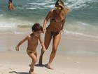 Com biquíni de oncinha, Livia Lemos brinca com o filho na praia