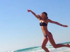 De biquíni, Bar Refaeli salta na praia e brinca com obra de Michelangelo
