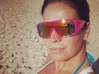 Com óculos grande, Solange Gomes corre na areia da praia 