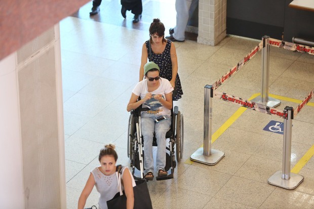 De cadeira de rodas, Maria Gadu embarca com namorada no aeroporto (Foto: Marcello Sa Barretto / AgNews)