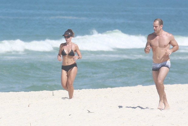 Carla Marins corre com seu marido na praia (Foto: Dilson Silva / Agnews)