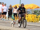 Ex-BBB Yuri pedala na orla na companhia de seu cachorro