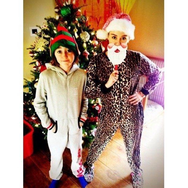 Miley Cyrus posa de macacão de oncinha e gorrinho de Papai Noel ao lado da irmã (Foto: Instagram)