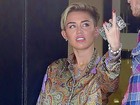 De shortinho, Miley Cyrus dá abaixadinha para apagar cigarro