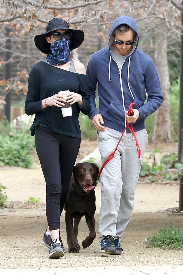 Anne Hathaway passeia com o marido e seu cachorro usando um lenço sobre o rosto (Foto: Grosby Group)