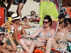 Carolina Ferraz curte praia de biquíni bicolor e mostra barriga chapada