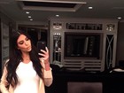 De vestido justinho, Kim Kardashian posa com a mão na barriga