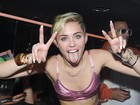 De top e saia curtinha, Miley Cyrus se diverte em festa