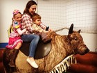 Gabriela Duarte brinca no touro mecânico com os filhos em festa junina