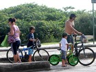Sem camisa, Domingos Montagner pedala com os filhos em praia carioca