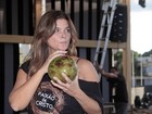 Tomando água de coco, Cristiana Oliveira posa em praça de Goiânia