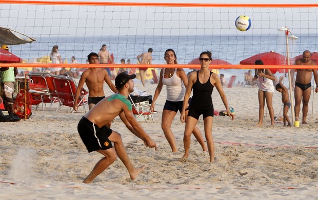 Imagem de pessoas jogando vôlei na praia.