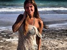 De vestido rendado, Cristiana Oliveira exibe o bronzeado na praia