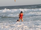 De vestido vermelho, Cássia Kis Magro entra no mar com o filho