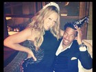 De vestido curtinho, Mariah Carey senta no colo do marido em festa
