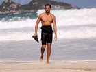Cauã Reymond caminha na praia após o surfe