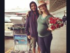 Pedro Scooby recebe Luana Piovani com flores em aeroporto